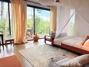 A bedroom with a large window, a bed, a chair, and a table. - Kaliwa Lodge (Machame)