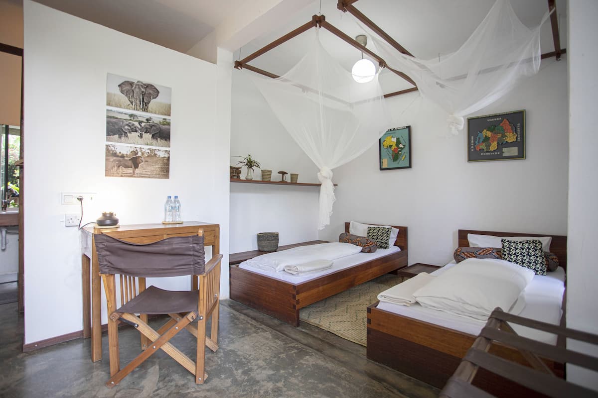 A room with a bed, a desk, and a chair. There are pictures on the wall and a map.