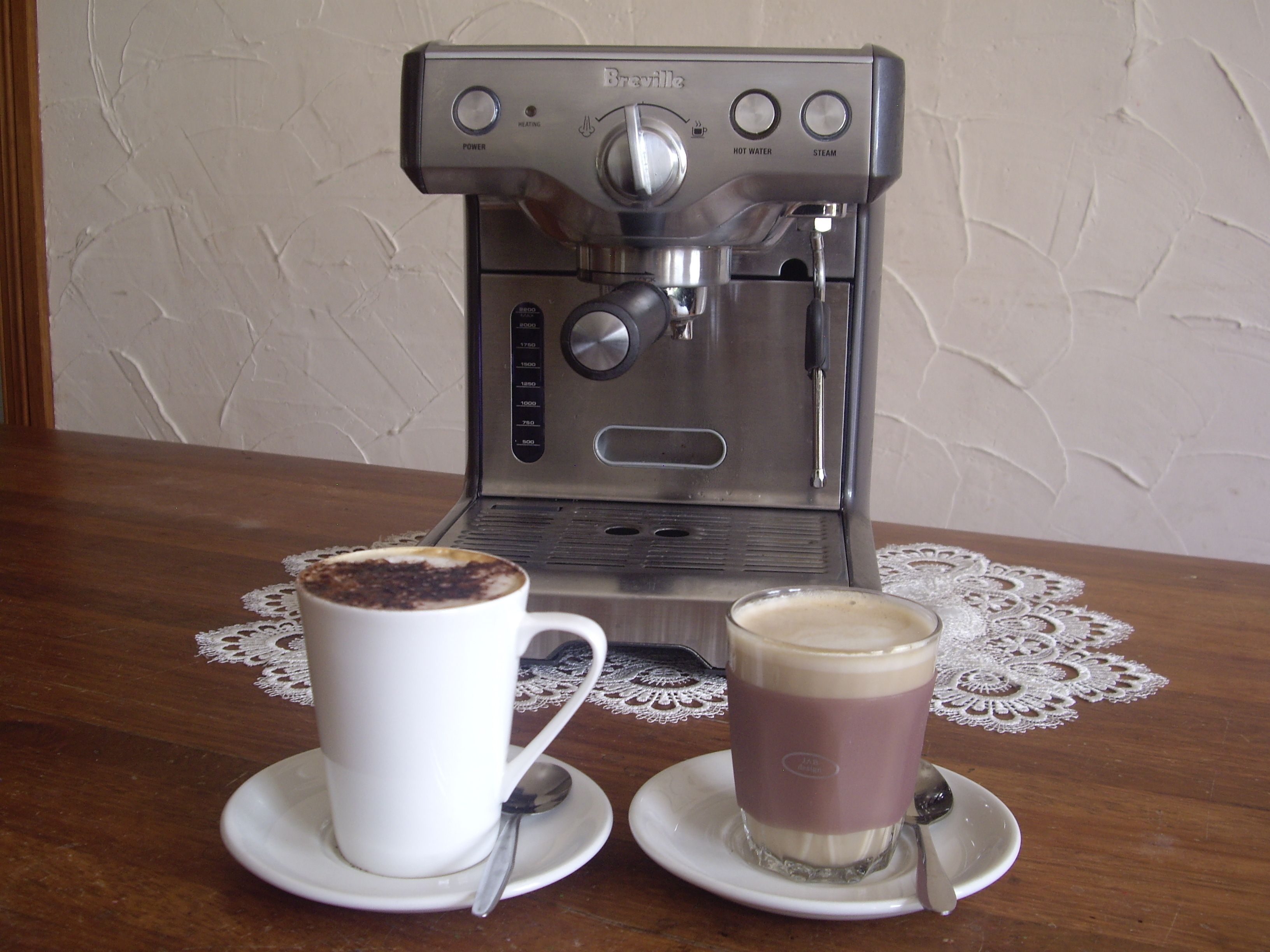 Eine Kaffeemaschine mit zwei Tassen Kaffee auf einem Holztisch.