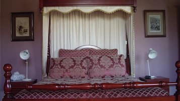 A four-poster bed with a canopy, two bedside tables, and two wall-mounted lamps.