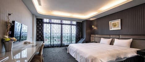 Una habitación de hotel moderna con una cama grande, un escritorio con silla, una mesita de noche, una lámpara y una ventana con vistas.
