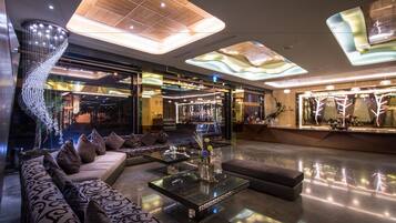 A modern lobby with a curved staircase, a seating area with patterned sofas, and a glass coffee table with decorative items.