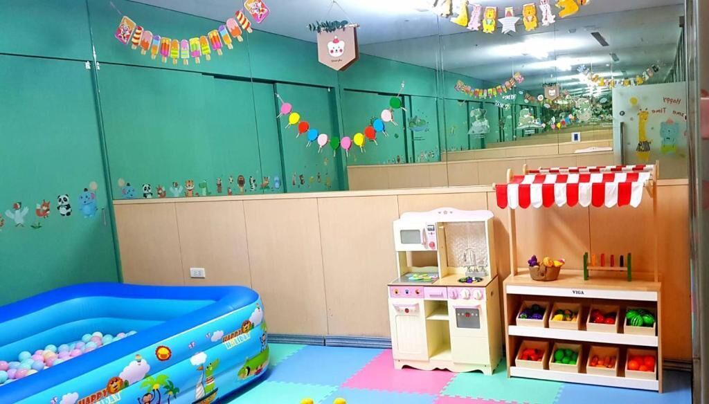 A children's playroom with a blue inflatable pool, a toy kitchen, and shelves with toys.