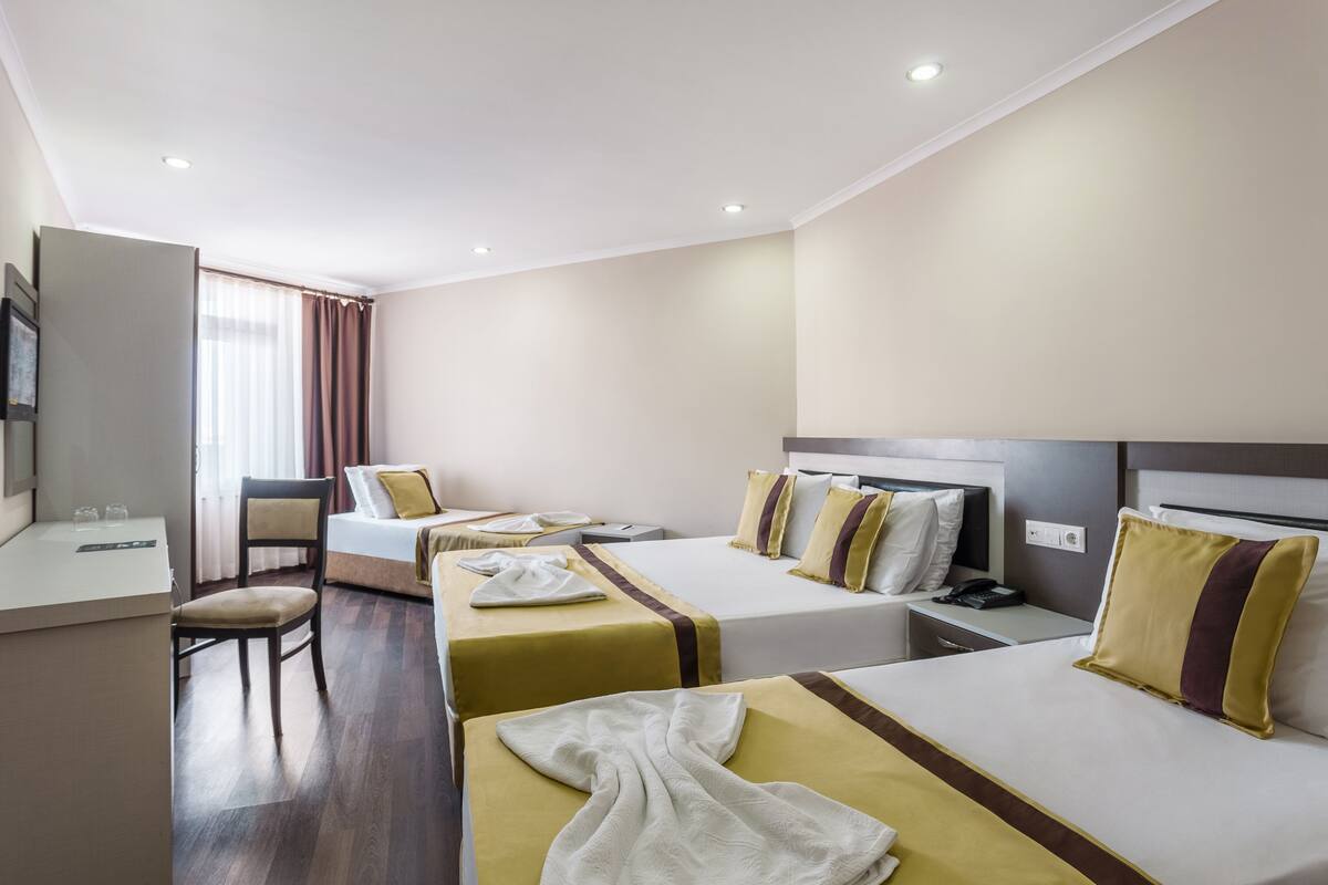 Una habitación de hotel con dos camas, un escritorio, una silla y un televisor.