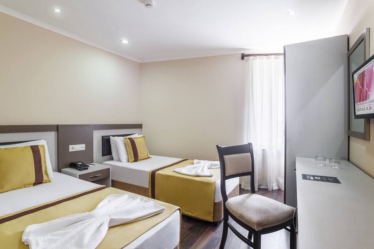 Una habitación de hotel con dos camas, un escritorio, una silla y un televisor.