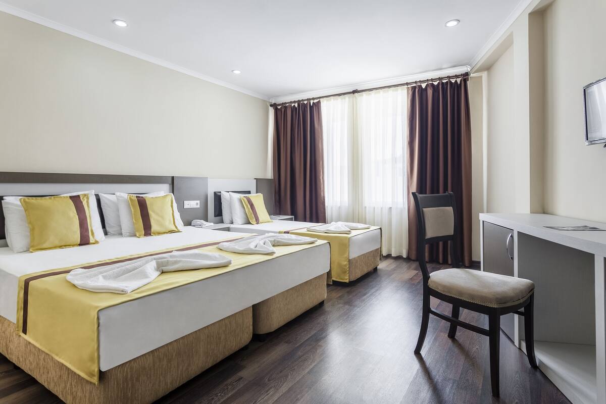 Habitación de hotel con dos camas, un escritorio y una silla.