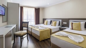 Hotellihuone, jossa on kaksi sänkyä, työpöytä ja televisio.
