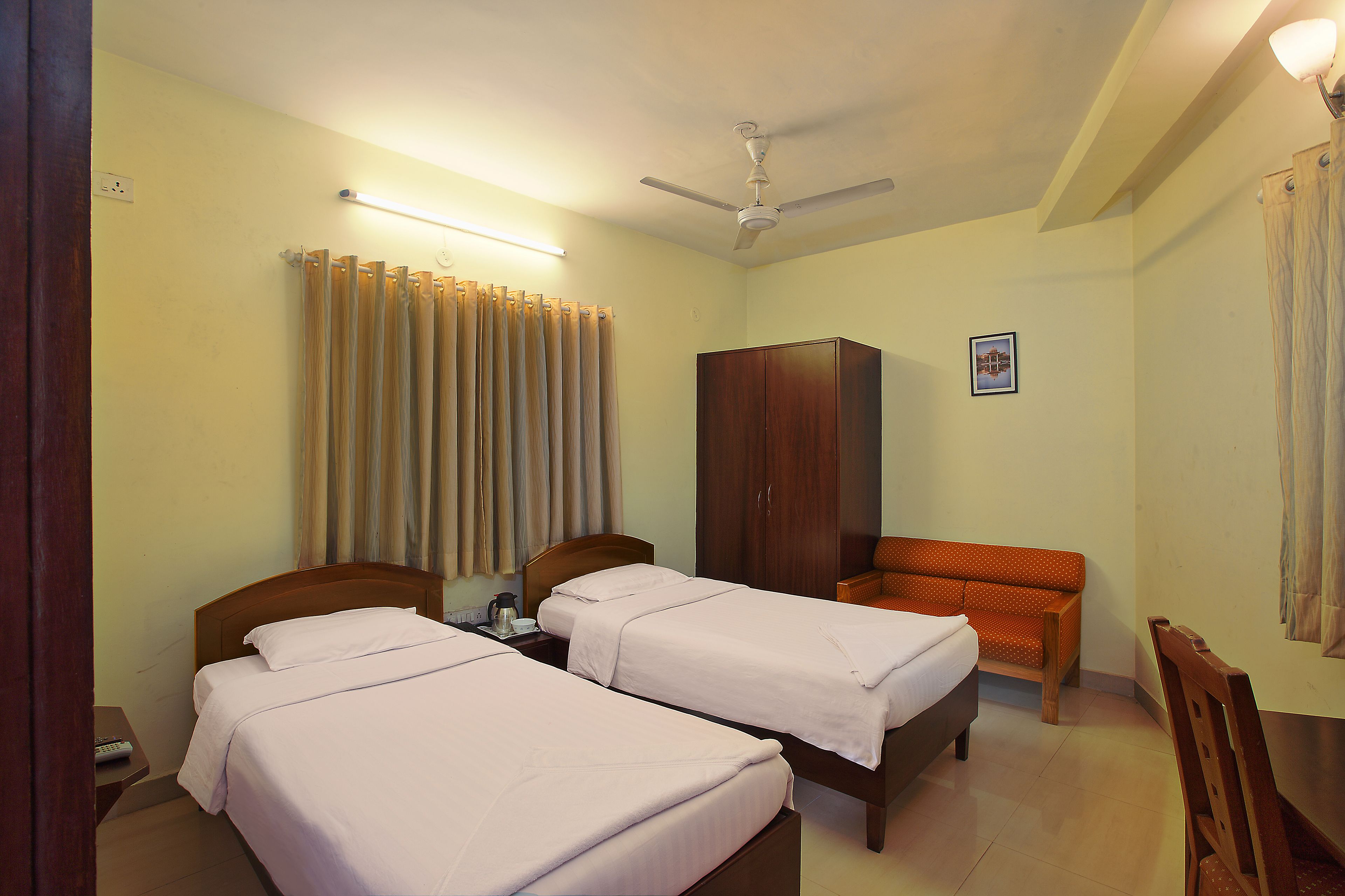 A hotel room with two beds, a wardrobe, a desk, and a chair.