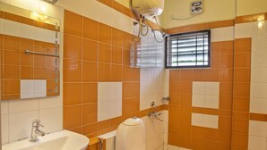 Un baño con baldosas anaranjadas y blancas, un lavamanos, un inodoro y una ducha.