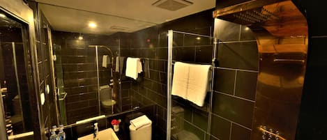 A modern bathroom with a glass-enclosed shower, a white sink, and a toilet.