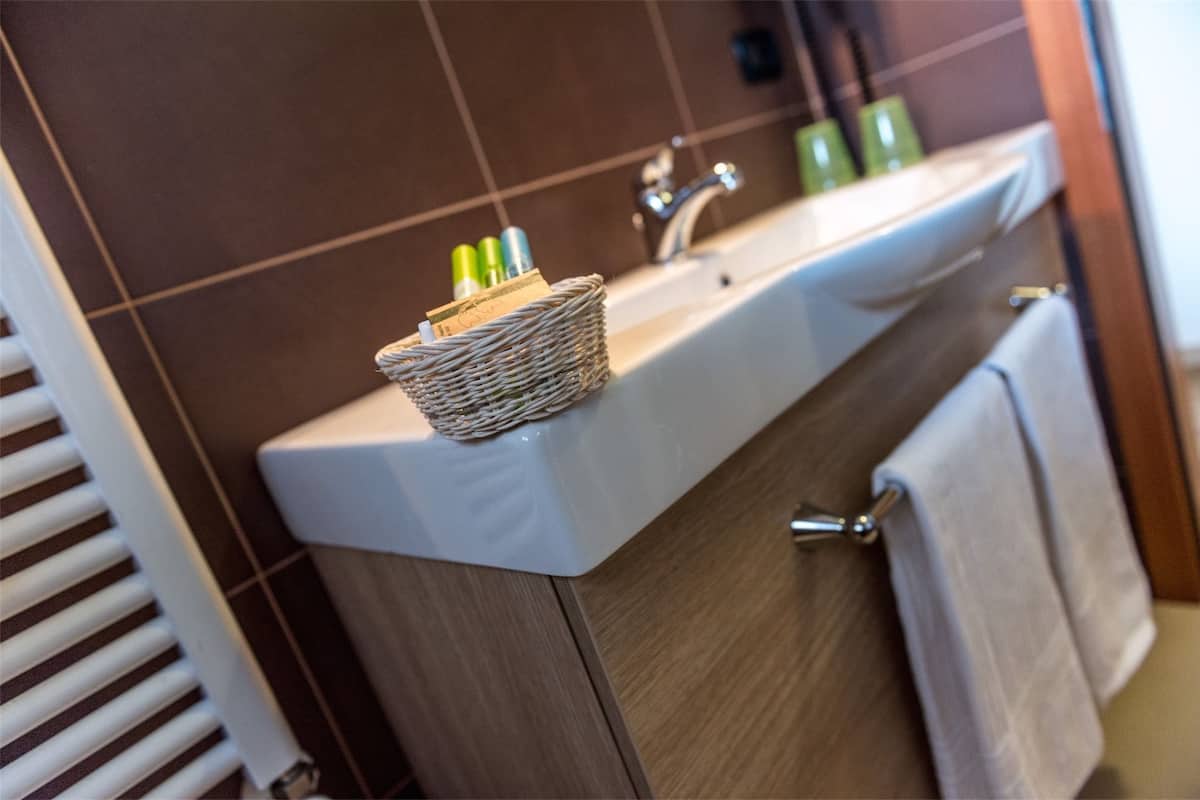 A bathroom with a white sink, a wicker basket on the countertop, and a towel hanging on the door.