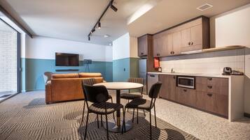 A modern kitchen with a dining area, a sofa, and a TV.