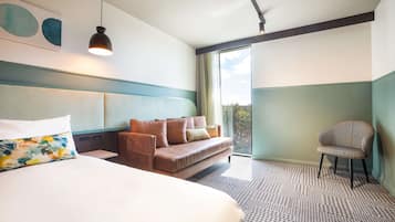 A hotel room with a large bed, a sofa, a chair, a ceiling light, and a view of the outdoors.