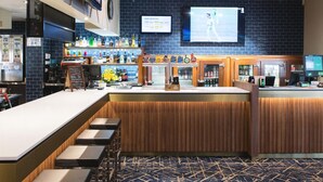 Zona de bar con una barra larga, taburetes, una pantalla de televisión y un tablero de menú.
