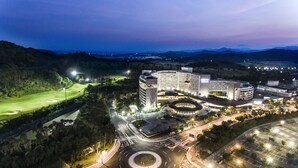 A modern hotel with a circular central courtyard, surrounded by landscaped areas and a golf course. - Lotte Buyeo Resort (Buyeo)