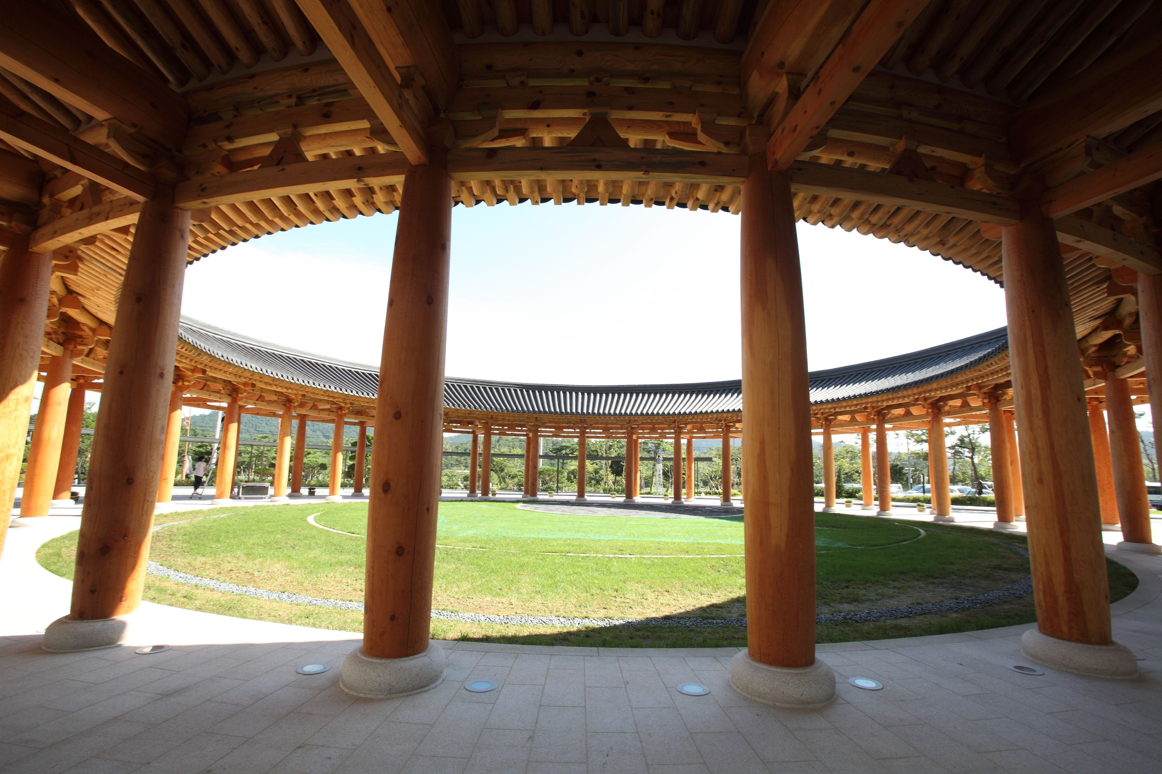 A traditional wooden pavilion with a circular layout and a central lawn.