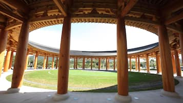 A traditional wooden pavilion with a circular layout and a central lawn.