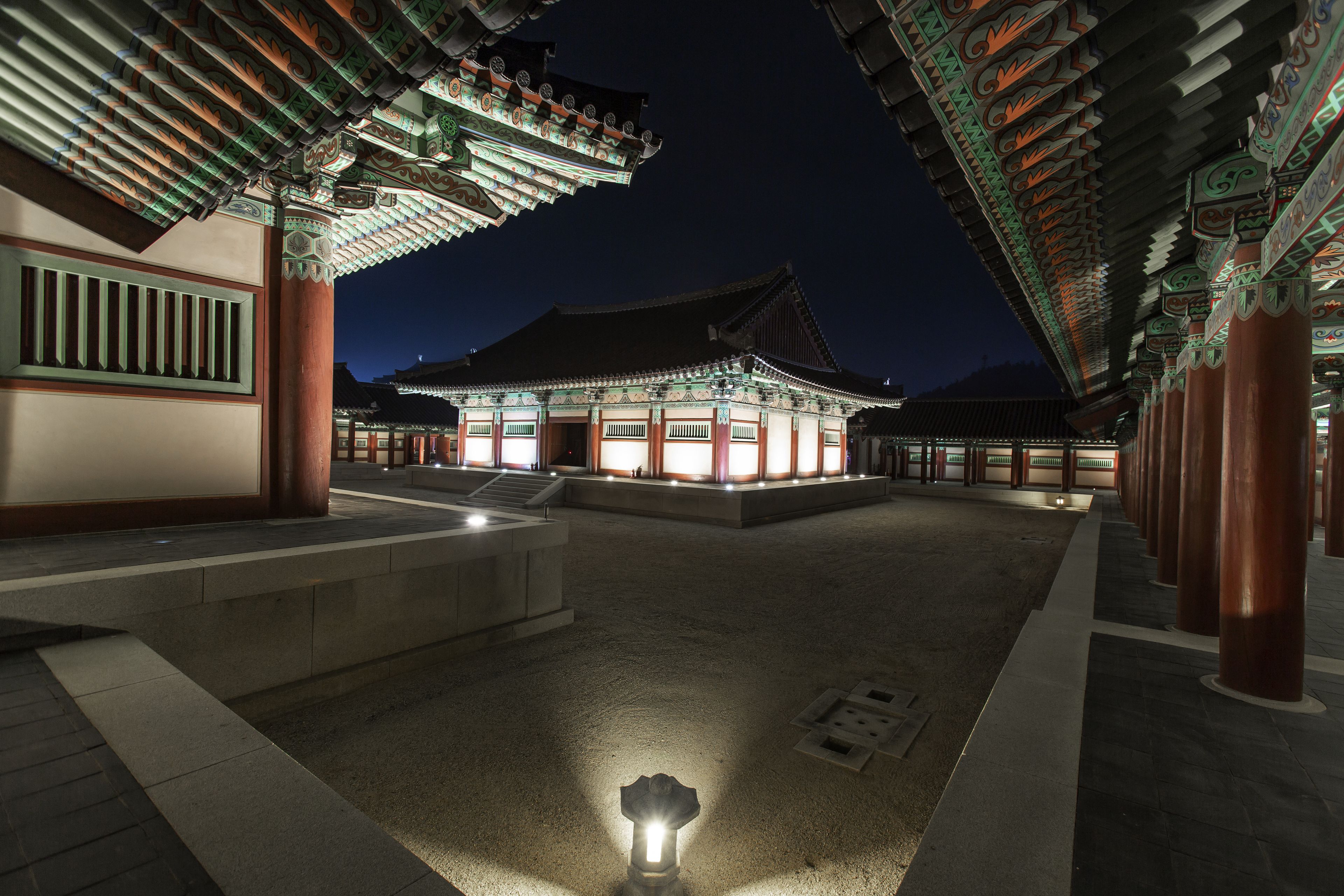 A traditional Korean building with a courtyard, illuminated by night lighting.