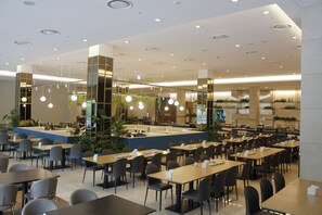 A spacious restaurant with multiple tables and chairs, a bar area, and a counter.