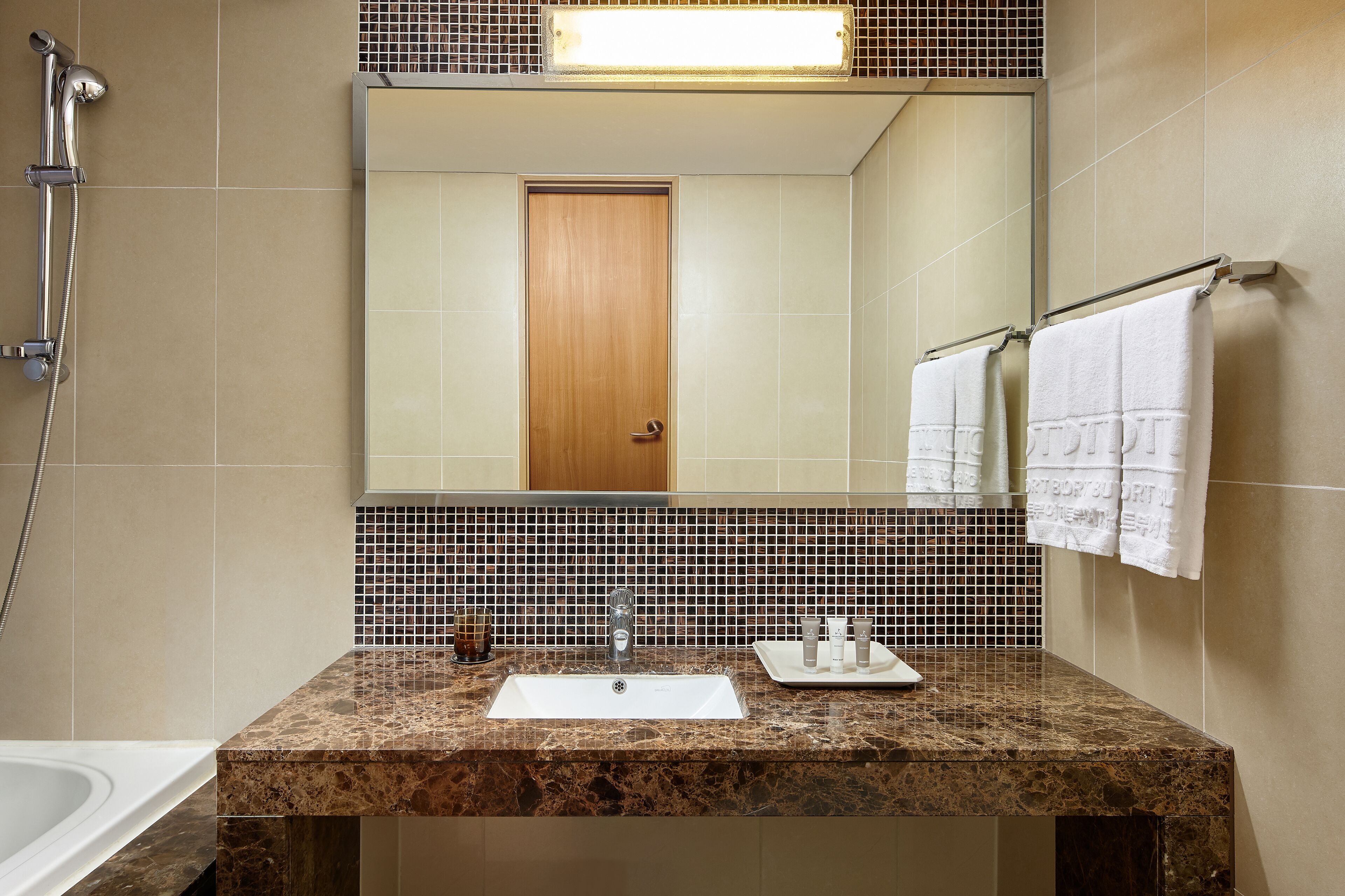 Un baño con lavamanos, espejo y toallero.