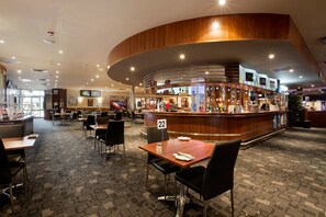 Un vestíbulo de hotel con un mostrador de recepción curvo, varias zonas de estar y suelo alfombrado.