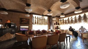Un restaurante con pared de piedra, una televisión y varias sillas y mesas.