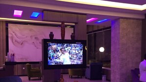 Una sala de estar moderna con televisor de pantalla plana, asientos cómodos e iluminación ambiental.