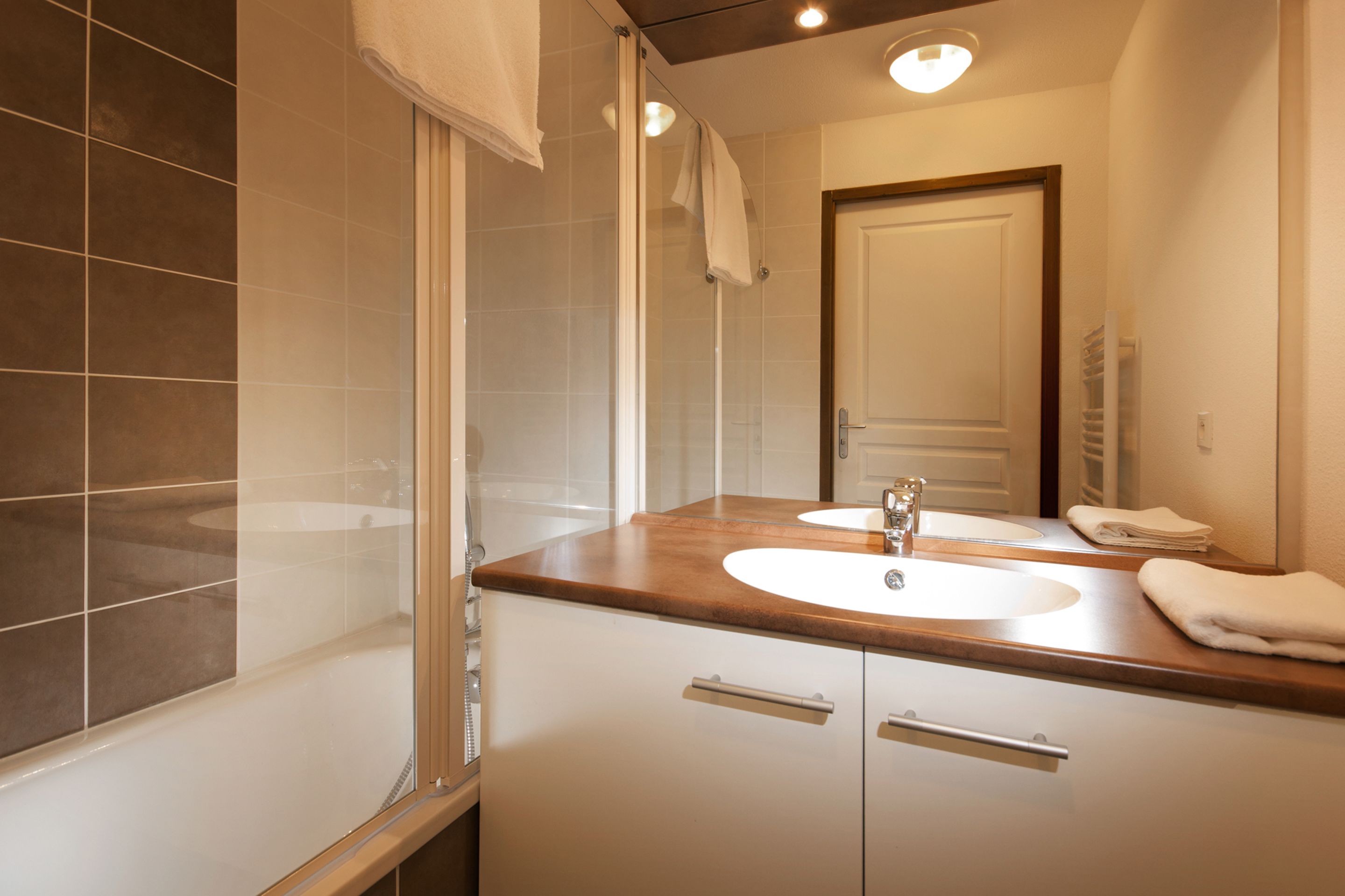 Un baño moderno con un espejo grande, un lavamanos y una ducha.