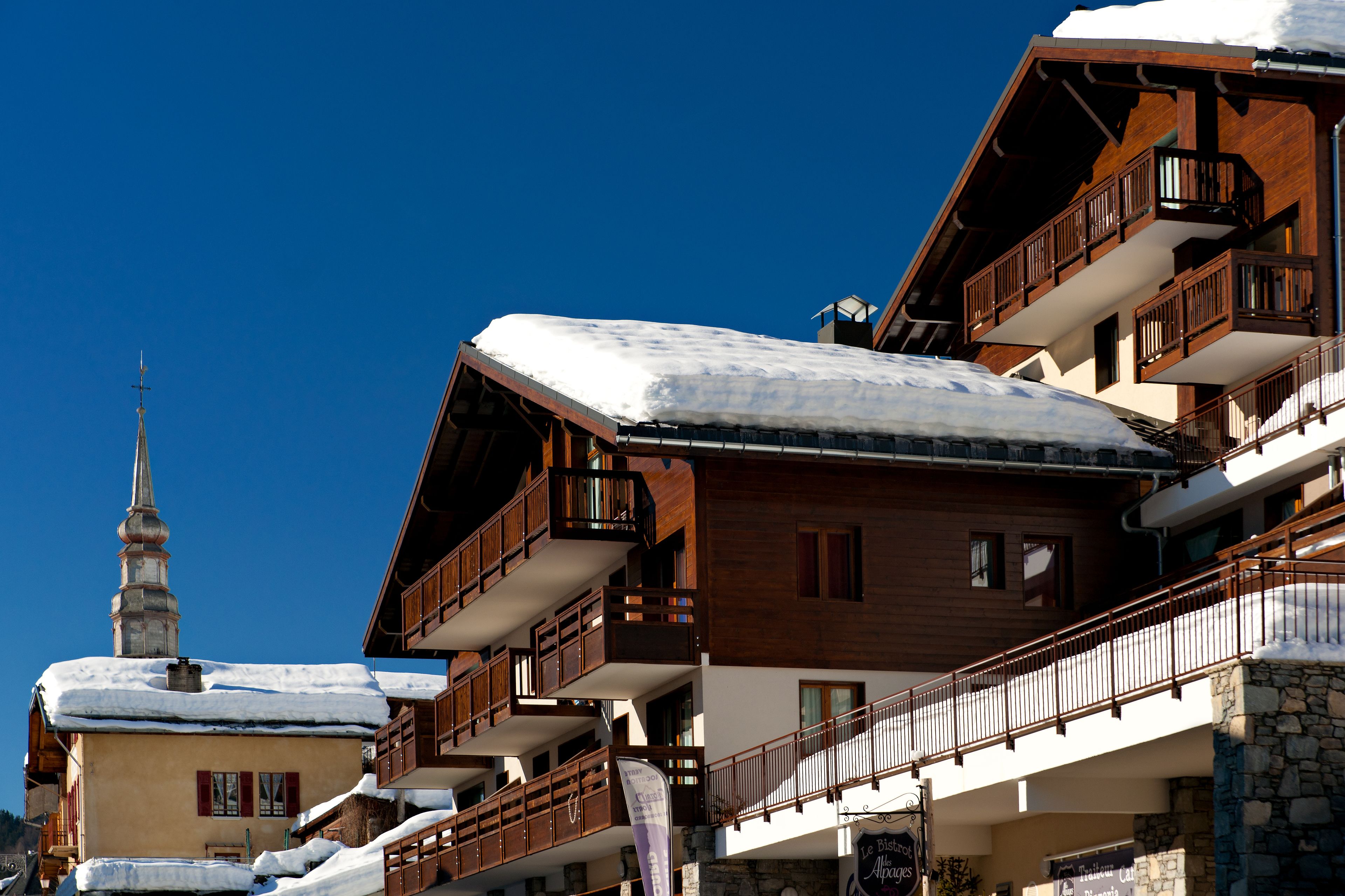 Un immeuble en bois à plusieurs étages, doté de balcons et d’un toit recouvert de neige.