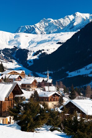 Ein verschneites Bergdorf mit Holzhäusern und einer Kirche.