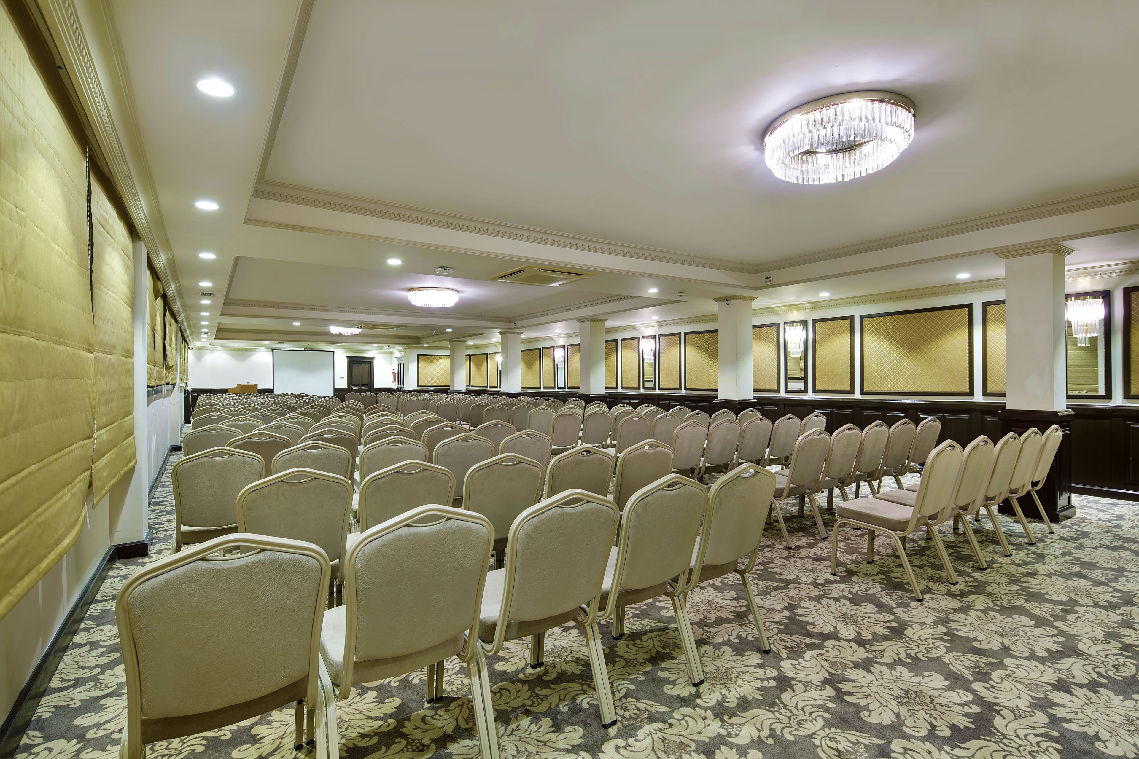 A large conference room with rows of chairs, a patterned carpet, and a chandelier.