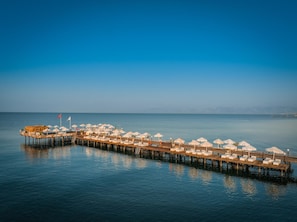 Een steiger met witte parasols en ligstoelen die zich uitstrekt over kalm water.