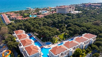 A resort with multiple swimming pools, a large central pool, and a view of the ocean.