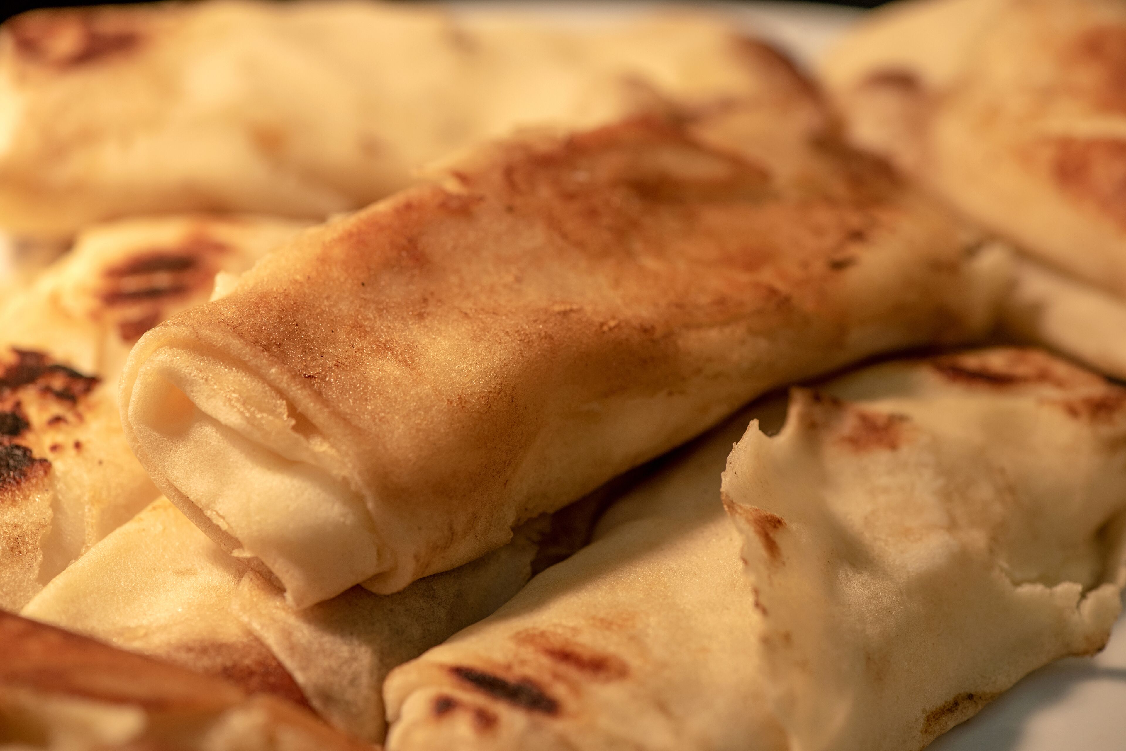 A close-up of a food item, likely a type of flatbread or pastry, with a golden-brown crust.