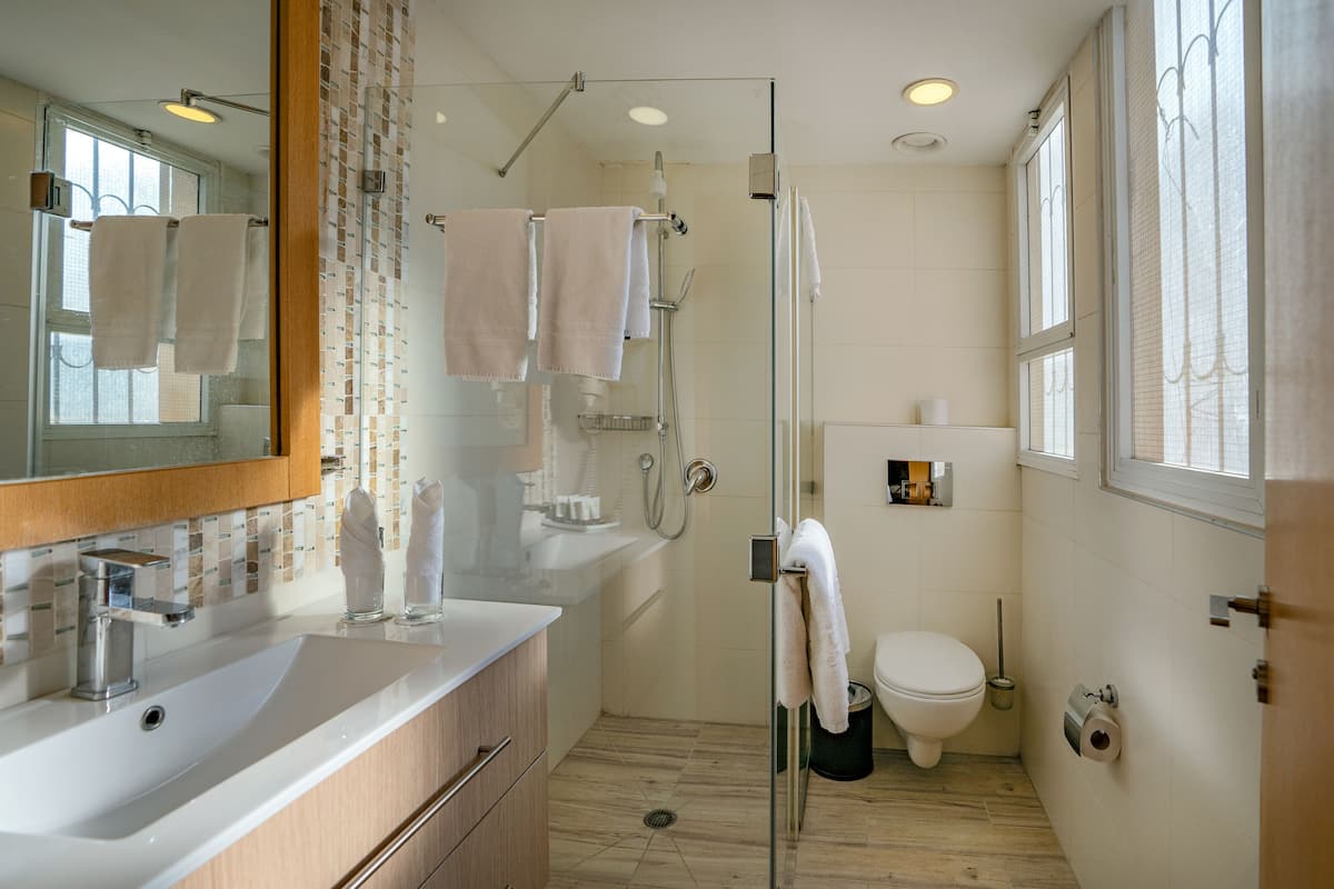 A modern bathroom with a glass-enclosed shower, a white sink, and a toilet.
