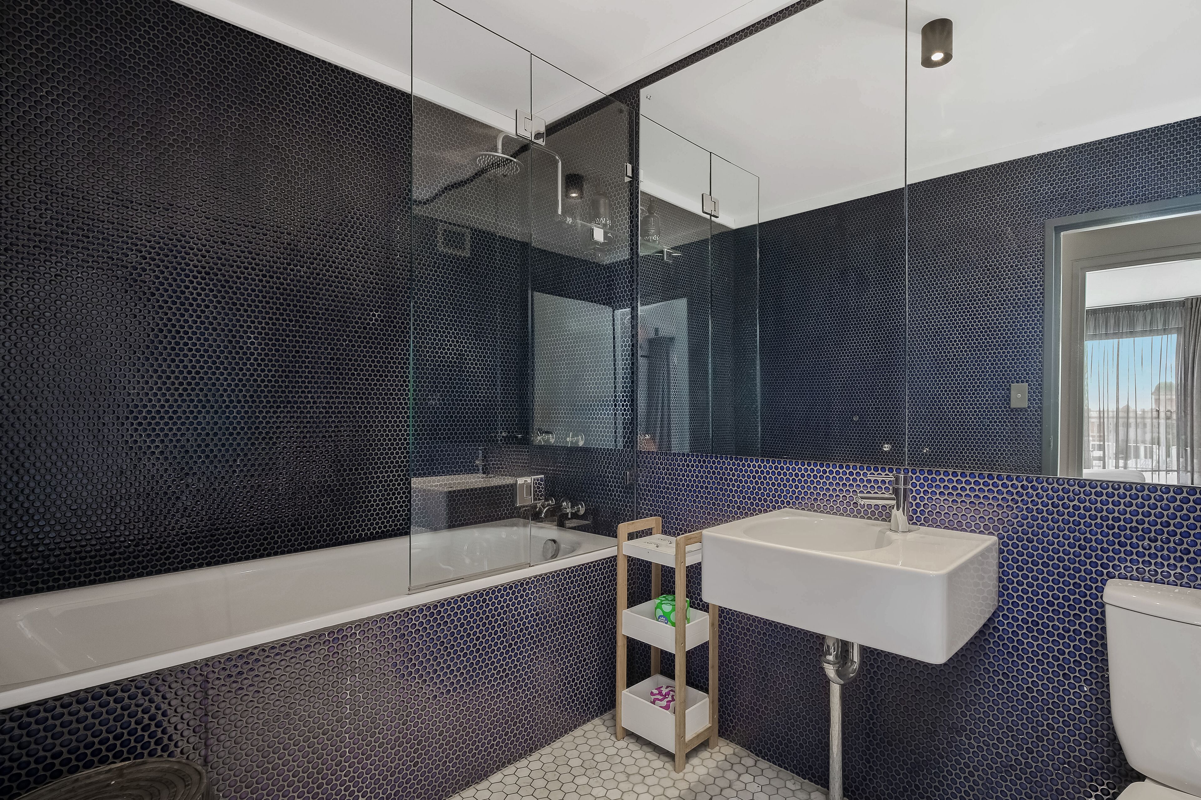 A modern bathroom with a large bathtub, a white sink, and a mirror.