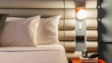 A neatly made bed with pillows, a bedside table with a lamp, and books.
