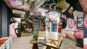 Un intérieur moderne avec un plancher en bois, une table ronde agrémentée d’une plante et une grande fresque murale.