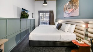 Une chambre d’hôtel avec un grand lit, un bureau, une chaise et une fenêtre avec des rideaux.