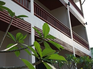 Un edificio de varios pisos con balcones y una vista de un árbol en primer plano.
