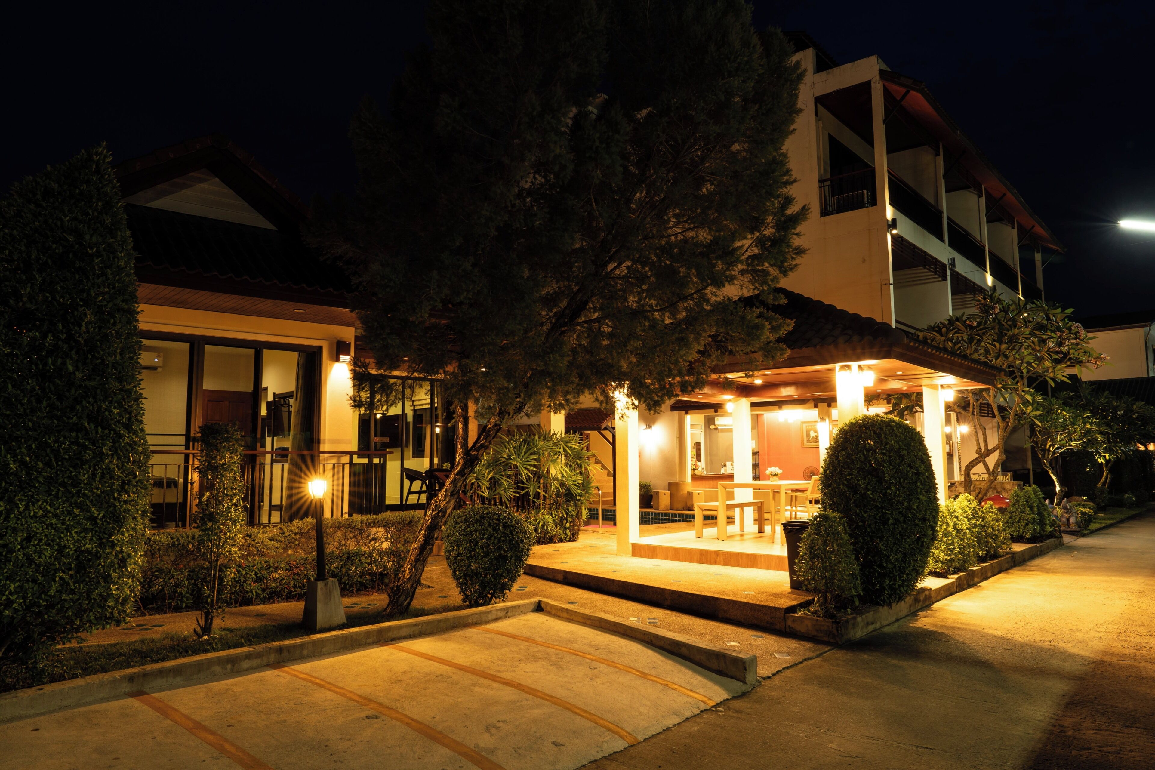 A building with a covered outdoor seating area, a staircase leading to the entrance, and a well-lit pathway.