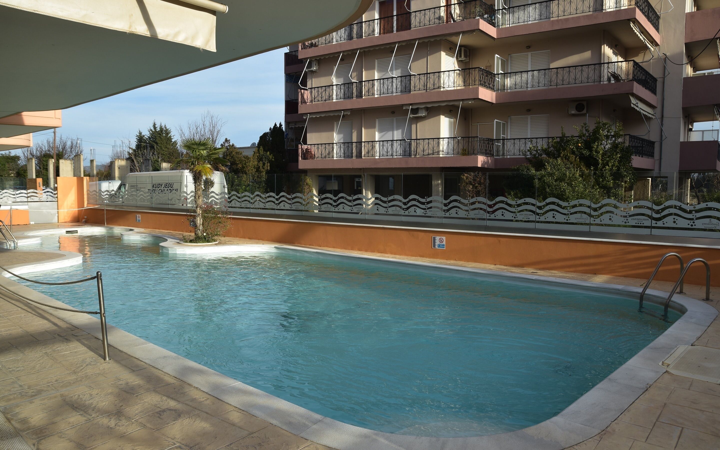 Una piscina con borde de baldosas, rodeada por un muro bajo con diseños decorativos.