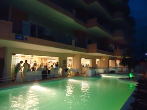 A pool area with a bar and dining area, surrounded by a multi-story building with balconies. - Philoxenia Hotel (Chalcis)