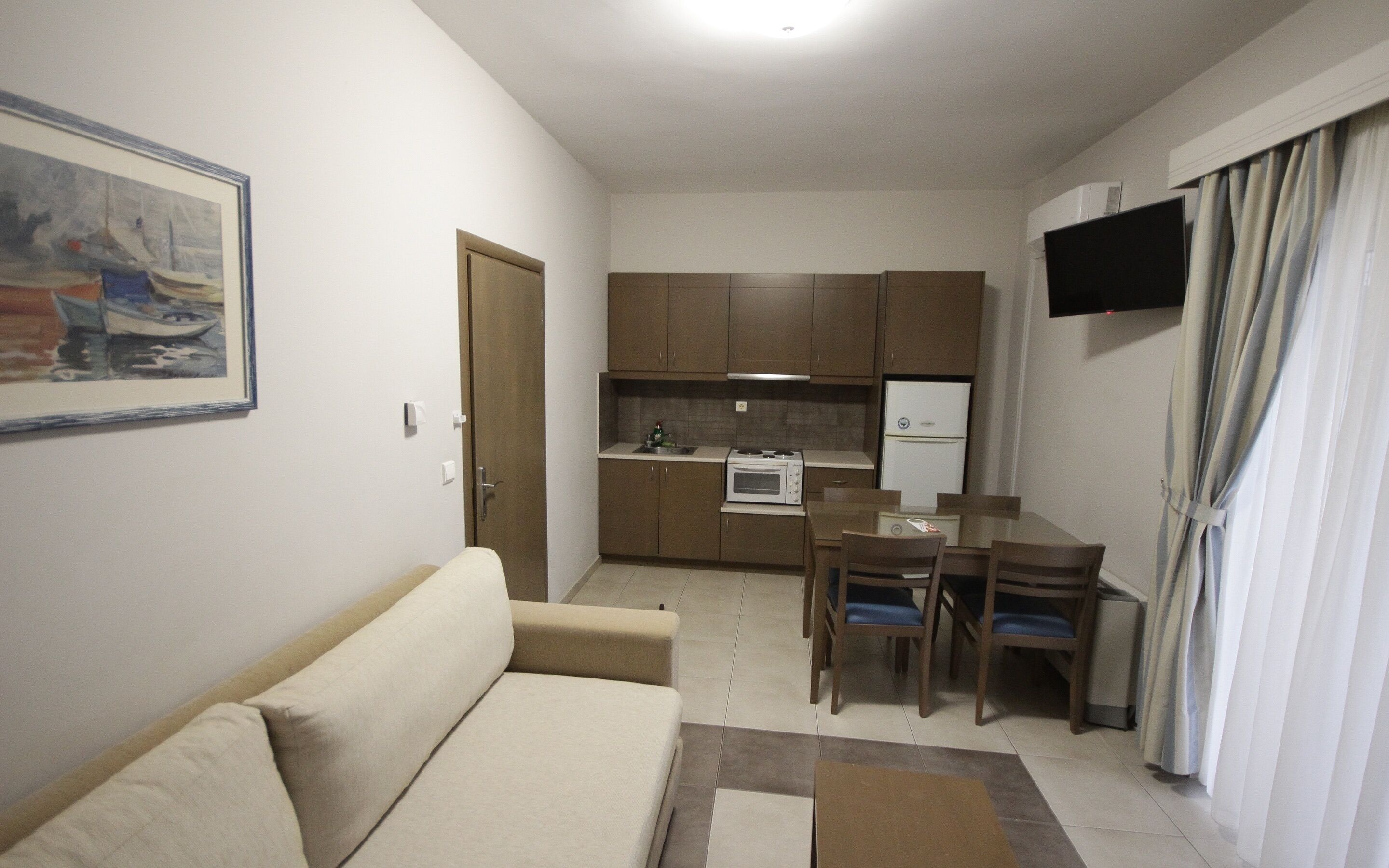 Un espacio habitable compacto con kitchenette, zona de comedor y sofá.