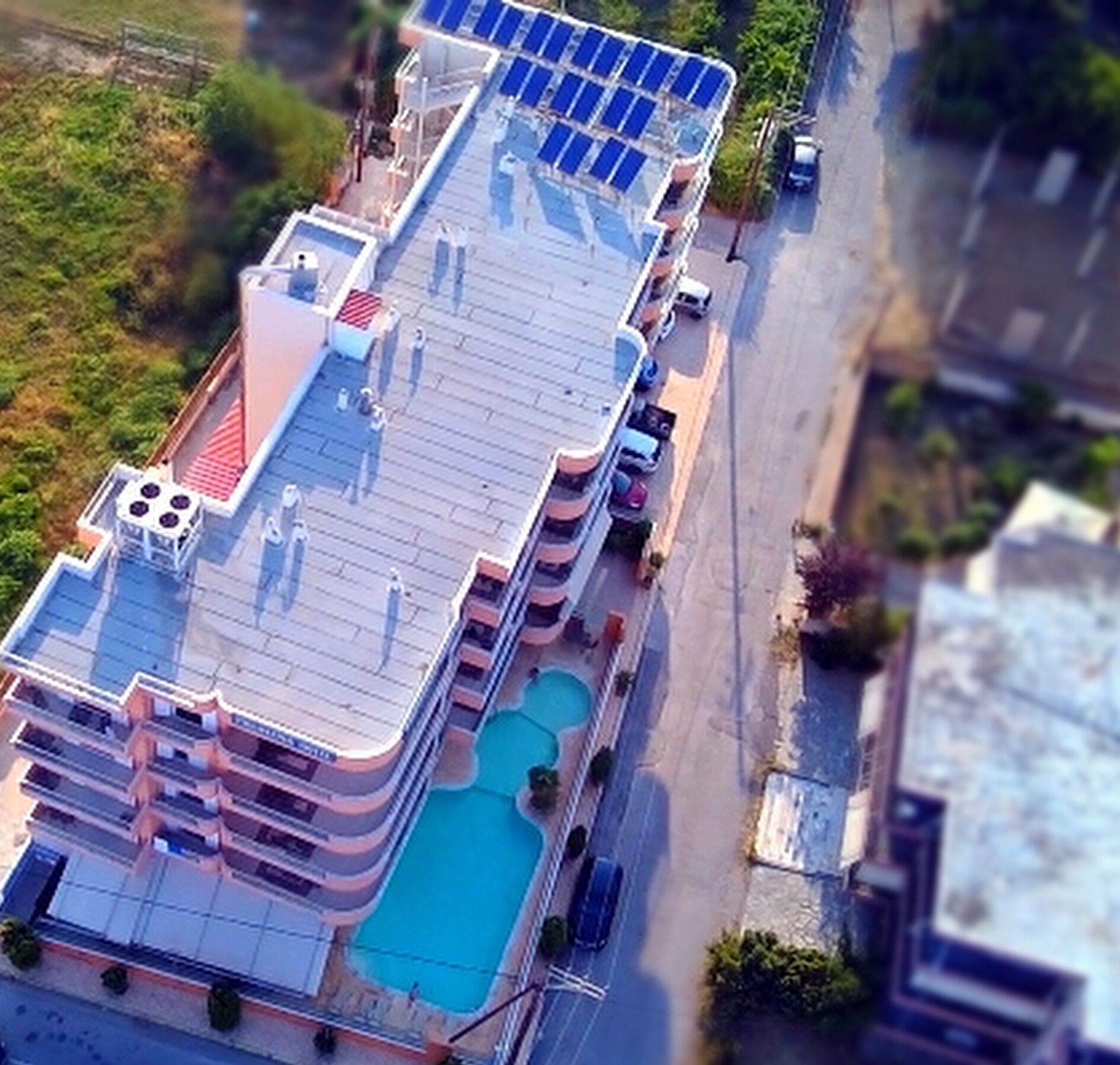 Un hotel de varios pisos con piscina en la azotea y paneles solares.