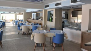 A restaurant with multiple tables and chairs, a kitchen area, and a large window providing natural light.