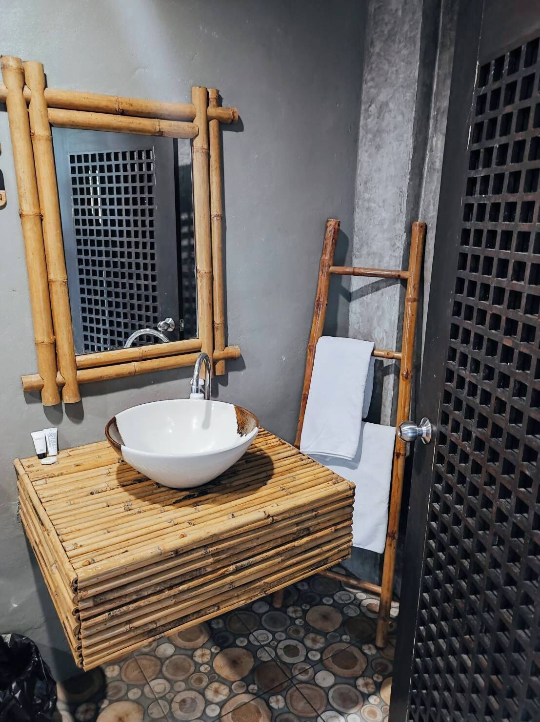 A bathroom with a bamboo vanity, a white basin, a mirror, and a towel rack.