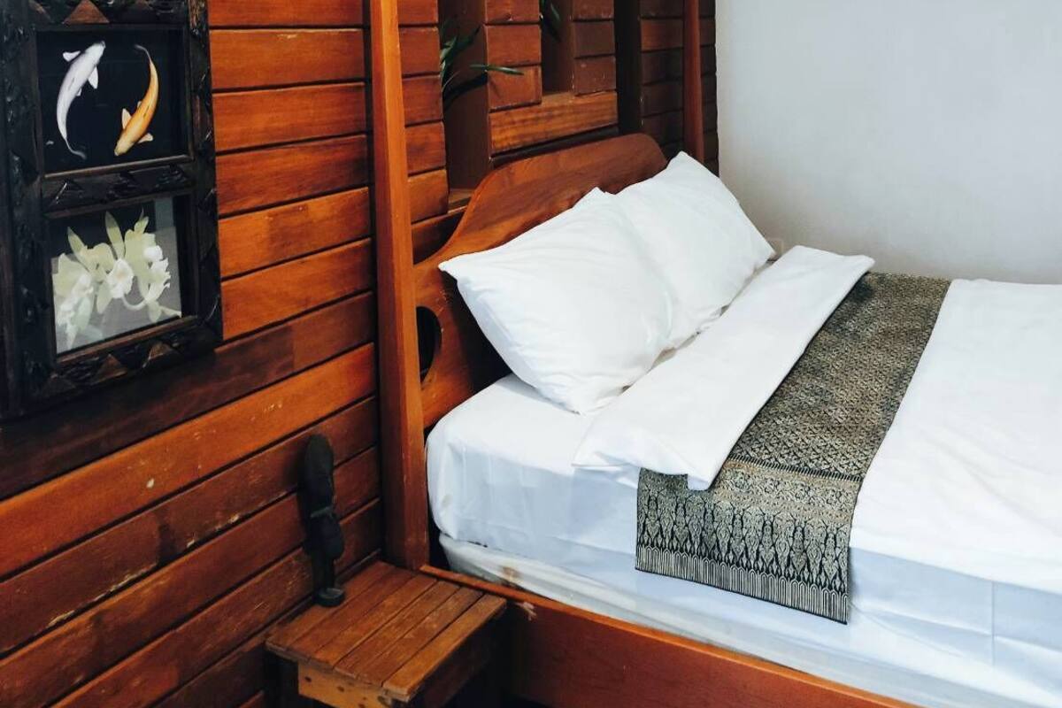 A wooden-framed bed with white bedding and a decorative pillow.