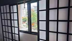 Ein Zimmer mit einer traditionellen japanischen Shoji-Schiebetür, einem kleinen Fenster und Blick auf die Straße.