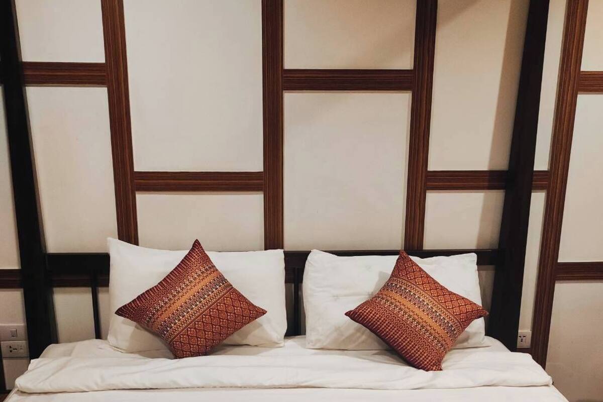 A bed with a headboard featuring a geometric pattern and two decorative pillows.